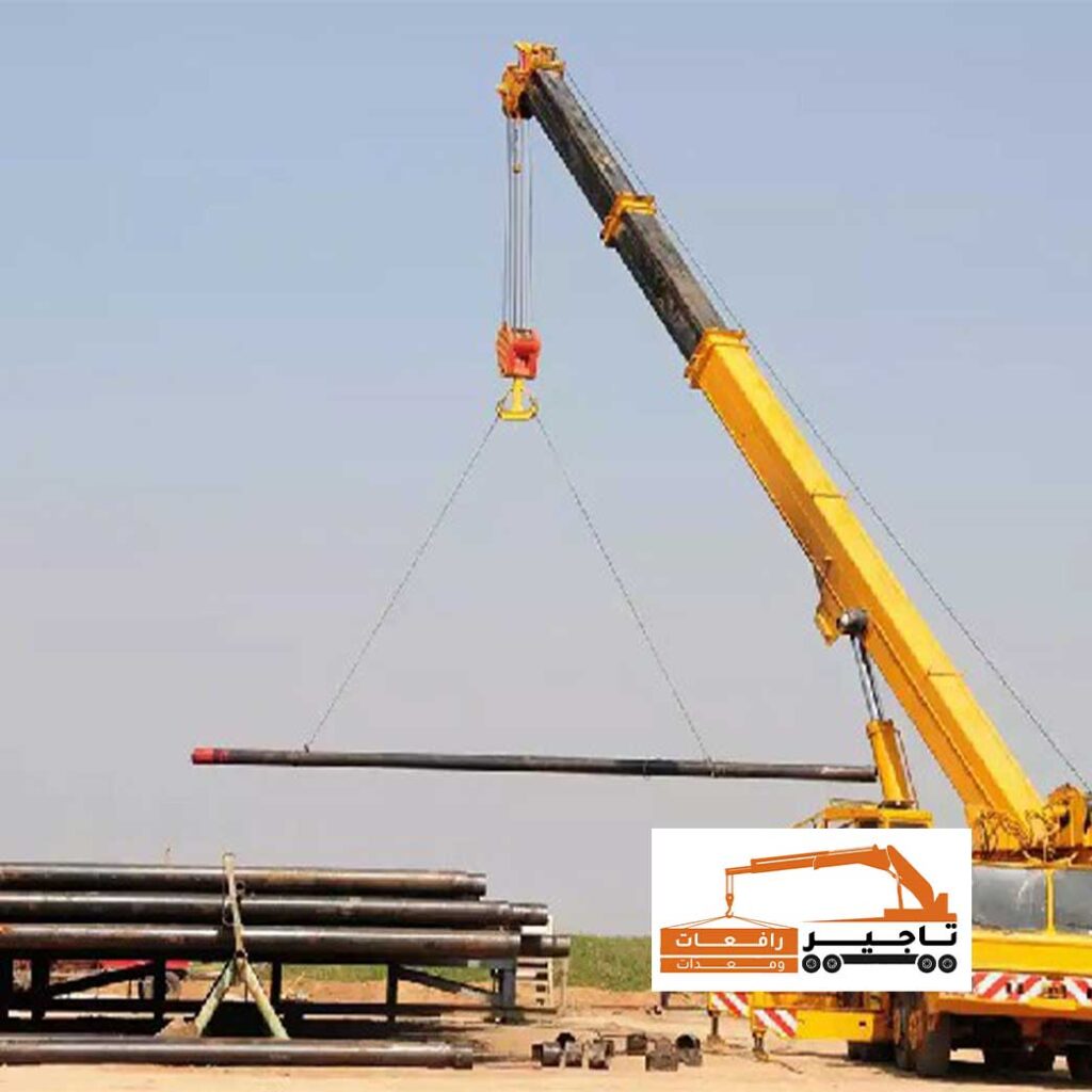 كرين يرفع قضيب حديدي طويل في موقع مفتوح.