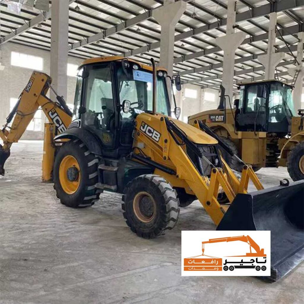 حفار JCB يعمل داخل مستودع كبير مع شيول خلفه.