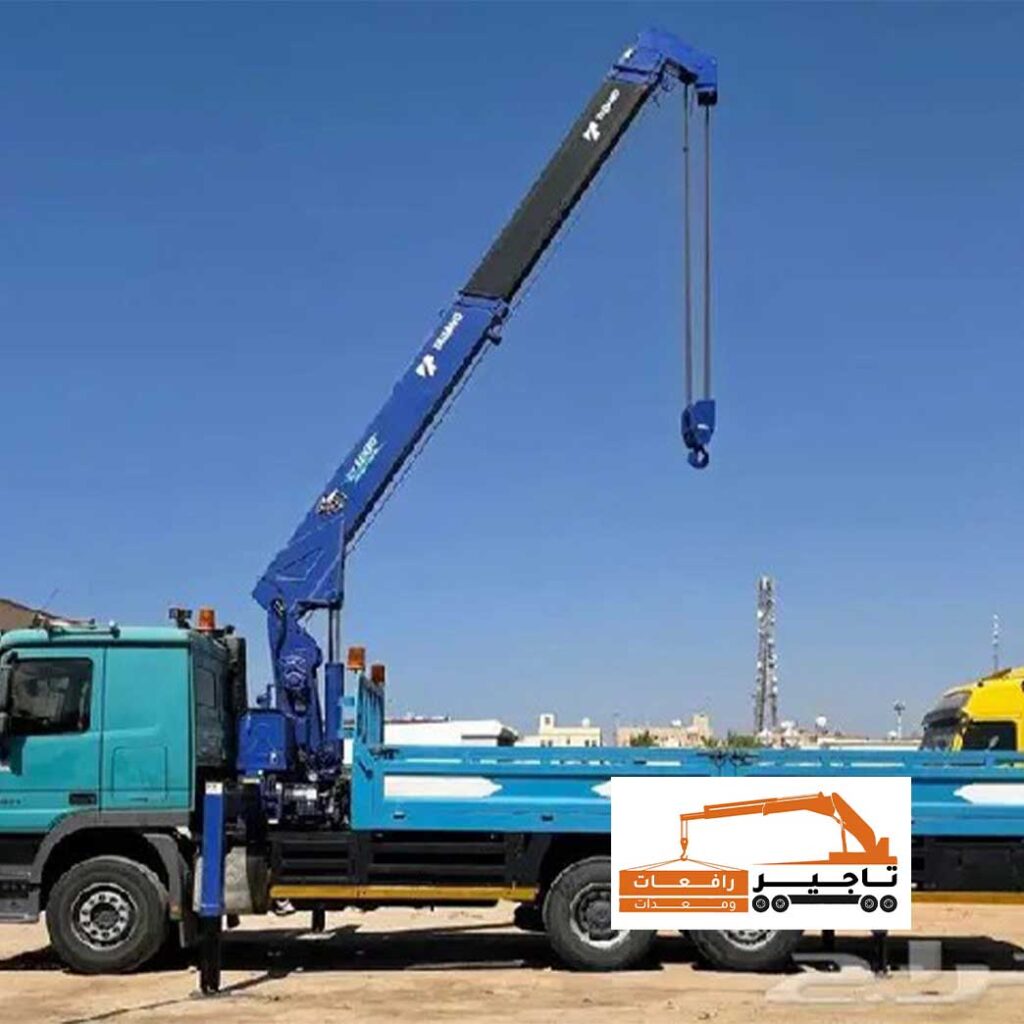 شاحنة خضراء مزودة بكرين أزرق طويل الذراع.